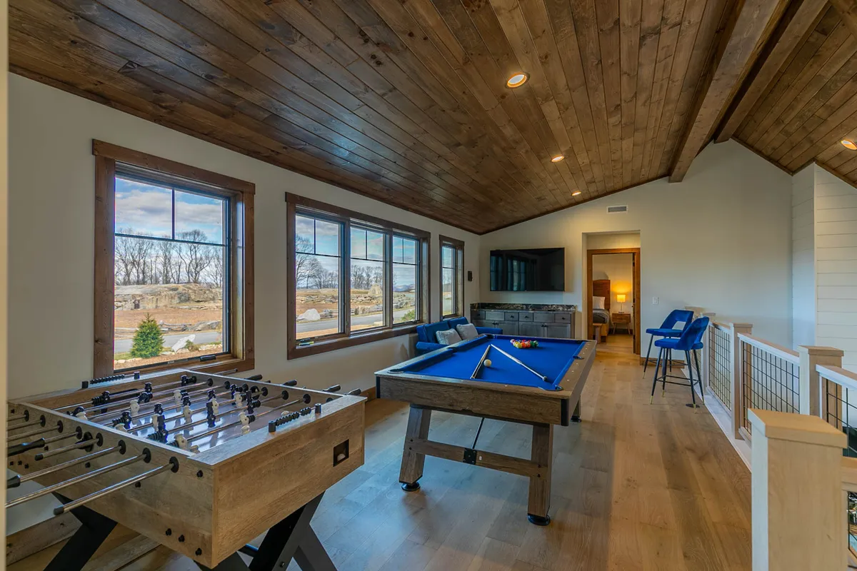 This image captures a lively game loft featuring both a foosball table and a pool table, set beside large windows that flood the space with natural light. A comfortable seating area is visible, inviting guests to relax and socialize between games. The vibrant atmosphere is enhanced by the presence of multiple entertainment options, perfectly aligning with the section's focus on playful competition and relaxation.
